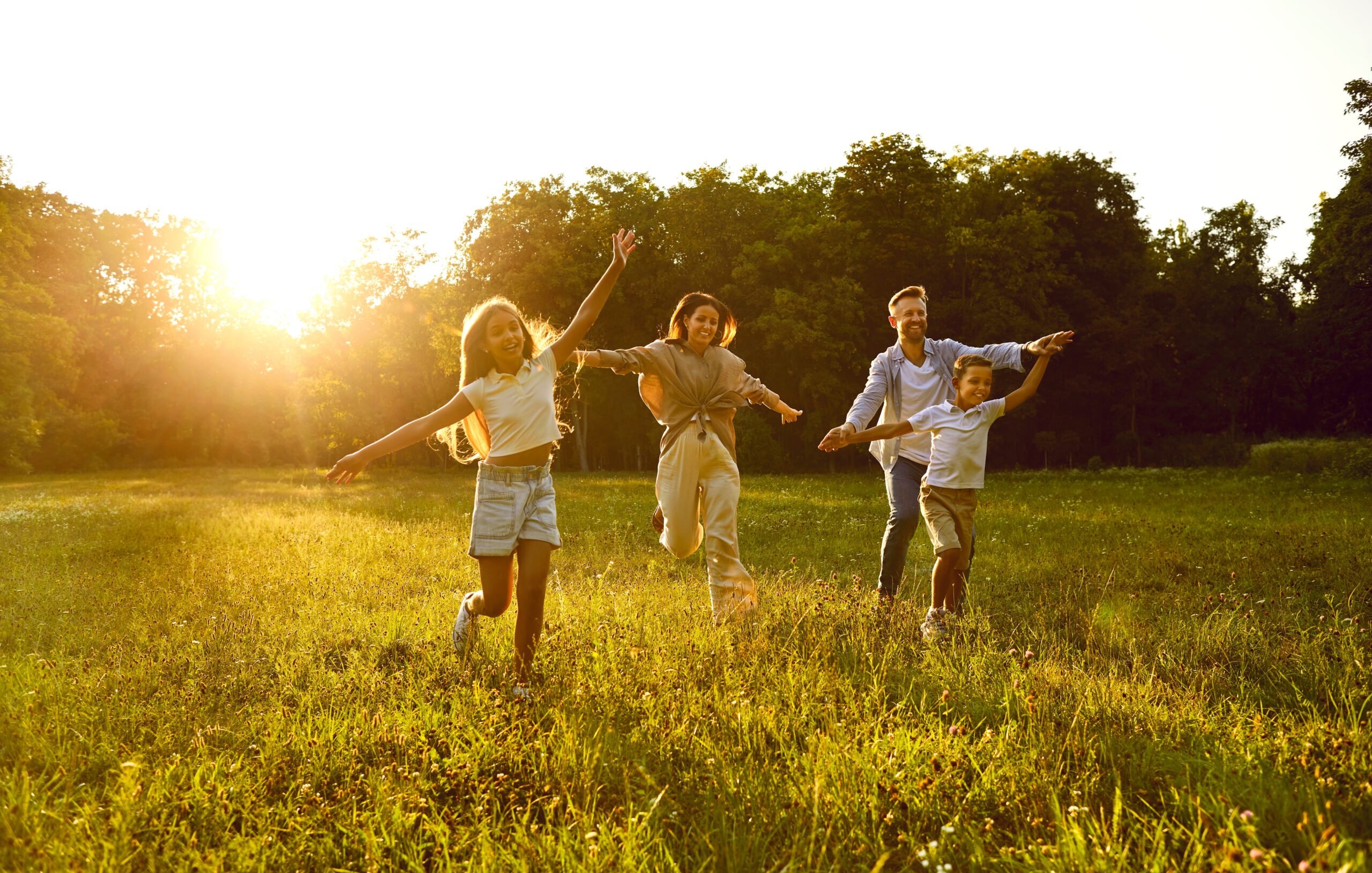A family runs happily through a field in the summer sunshine